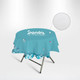 A round table cover in teal featuring floral designs and a logo, draped over a folding table.