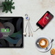 A wheat straw charging cable in white, connected to a phone and a tablet, on a marble tabletop with a coffee cup.