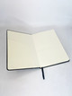 An A5 notebook with 240 blank pages, featuring a black cover and a ribbon bookmark. It includes a pocket inside.