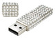 A silver USB flash drive encrusted with clear diamonds, featuring a shiny, blingy design and a removable cap.