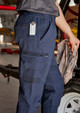 Navy work pants with cuffed hems, featuring multiple pockets and a logo. Suitable for various work environments.