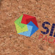 A cork notebook featuring a colourful geometric logo, set against a natural cork background.