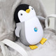 A penguin-shaped plush travel pillow in black, white, and yellow, featuring a small logo on its belly.