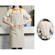 A poly-cotton canvas full bib apron in beige with a yellow neck strap and front pocket. Features a branding logo.