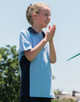 A light blue and navy polo shirt on a smiling child, with a logo on the chest.