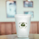 A frosted plastic stadium cup with a printed design of a T-shirt and heart, set in a blurred indoor background.