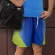A pair of custom men's sports shorts in blue and lime green, paired with a black duffel bag.