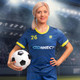 A female model wearing a blue soccer jersey with yellow accents, holding a black and white soccer ball.