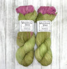 Wonderland Yarns Cheshire Cat, light fingering One-of-a-Kind Yarn. This colorway  features a pea green base with a burst of pale pink and purple.