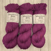 Wonderland Yarns Cheshire Cat, light fingering One-of-a-Kind Yarn. This colorway  features a purple-pink base, with specks of magenta.