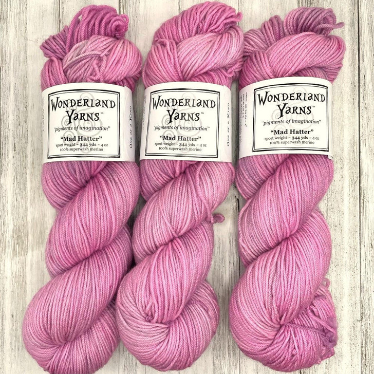 Mad Hatter Hand-Dyed One-of-a-Kind Yarn from Wonderland Yarns. This sport-weight colorway is a variegation featuring a pale pink base with hints of light charcoal, and specks of bright pink.