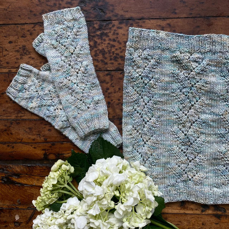 The Trailing Vines Cowl & Mitt pattern set by Wonderland Yarns features and delicate lace pattern that uses simple stitches, allowing both the cowl and mitts to be knit quickly with just one skein.