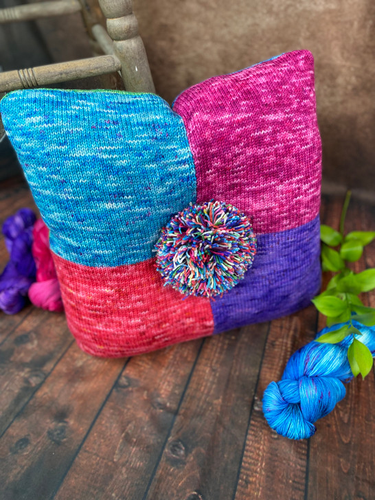 Bold, bright, and full of personality, this colorful pillow by Deborah George adds a playful pop to any space. Made with eight vibrant shades and topped with a cheerful pom-pom, it’s as fun as it is cozy.