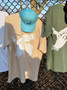 CHAMPAGNE WHITE SMOKE RESPONSIBLY SOUVENIR TEE ON MESH MERCHANDISE DISPLAY RACK IN URBAN SETTING