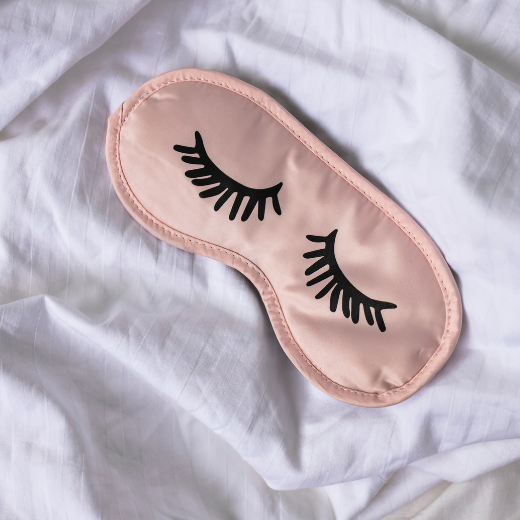 Sleep mask on bed sheets promoting proper sleep to help with dark circles under the eyes