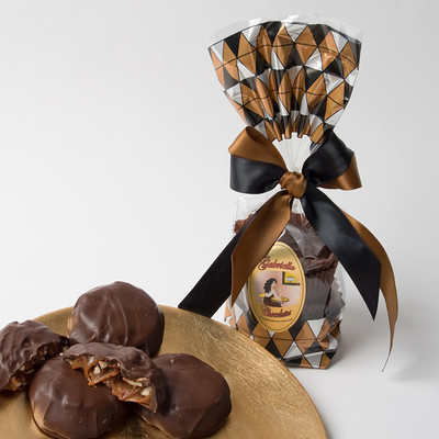Dark Chocolate Caramel Pecan Clusters: Sea salt caramel oozes around the oven- toasted pecans.  Once these clusters of caramely pecans are firm enough to handle, They are covered in Premium 60% Dark Chocolate.  (½ lb) Gold striped gift bag, hand tied with gold & ivory ribbon.