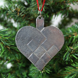 Silver pewter pleated heart Christmas ornament hanging on a pine tree.