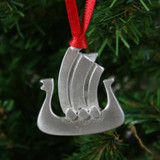 Pewter Viking ship ornament with red ribbon hanging on a Christmas tree.
