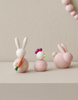 Pink wooden bunny and chicken figures on a light surface.
