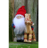 Scandinavian Tomte figurine with white beard and red hat standing beside a straw goat.