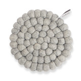 Top-down view of a circular raw grey wool ball trivet with a brand tag.