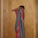 Black dishcloth hanger with a colorful patterned cloth draped over it on a wood cabinet.