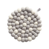 Round grey wool felt ball trivet with scattered white dots and branded tag.