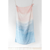 A linen tea towel in rose and blue gradient, hanging against a white wall.