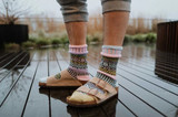 Close-up of mismatched multicolored patterned crew socks in lilac paired with tan sandals.