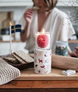 Klinta scented soy candle in a glass jar, resting on its illustrated gift box on a wooden board.