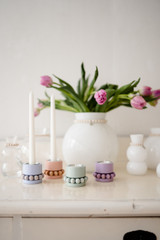Melon-colored Aarikka wooden bead tealight holder on a white surface, with tulips and other candleholders.