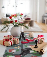 Gray Ekelund organic cotton table runner featuring a festive red and green Christmas elves pattern.