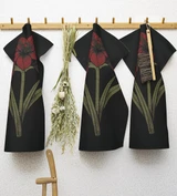 Three black cotton tea towels with red amaryllis patterns hanging on a wooden rack.