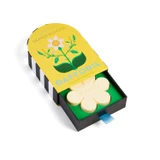 Yellow and black matchbox-style box with floral art, open to reveal a flower-shaped white soap.