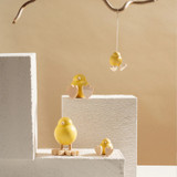 Hanging yellow wooden chick ornament by Aarikka with light wood feet on string.