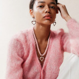 Soft pink wooden bead and silver heart dangle earrings worn by a model.