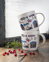 Two white mugs stacked, featuring Norwegian icons like fish, flags, and houses.
