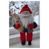 Red-hatted Tomte doll with white beard, holding a sack and skis, felt and wood construction.