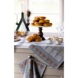 Grey Ekelund cotton table runner with St. Lucia motifs and hearts, styled on a kitchen counter.