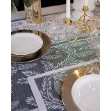Green and white Ekelund Frostgren tea towel featuring pine branch patterns, used as a placemat in a festive table setting.
