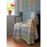 Cream-colored wool throw blanket draped over a wooden chair, featuring colorful floral patterns.