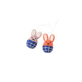 Two felt bunny ornaments, pink and orange, with blue checkered bottoms, white string.