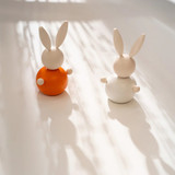 White wooden rabbit figurine with long ears, orange body, and wooden arms.