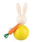 Wooden bunny figurine with yellow body, carrot, and green ribbon.