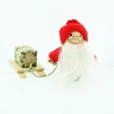 Wooden Tomte Santa figurine wearing a red knit hat and holding a sled with a gift.