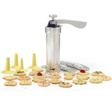 Silver aluminum cookie press with 4 yellow icing tips, 20 discs, and baked cookies.