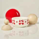 Aarikka Tonttu Christmas Elf ceramic bowl with red love elf patterns, flanked by wooden sphere toys.
