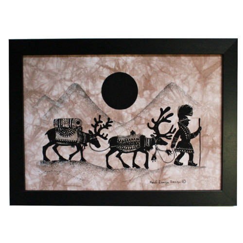 Black framed batik art of a Sami person with reindeer, black and brown, with mountains and sun.