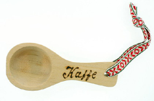 A light wood coffee spoon with a burnt-wood "Kaffe" label and a red, white, and green patterned ribbon.