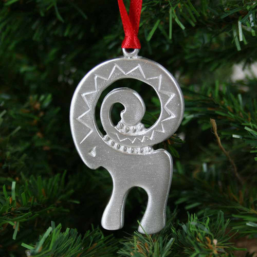 Pewter Julbock ornament with red ribbon hanging on a Christmas tree.
